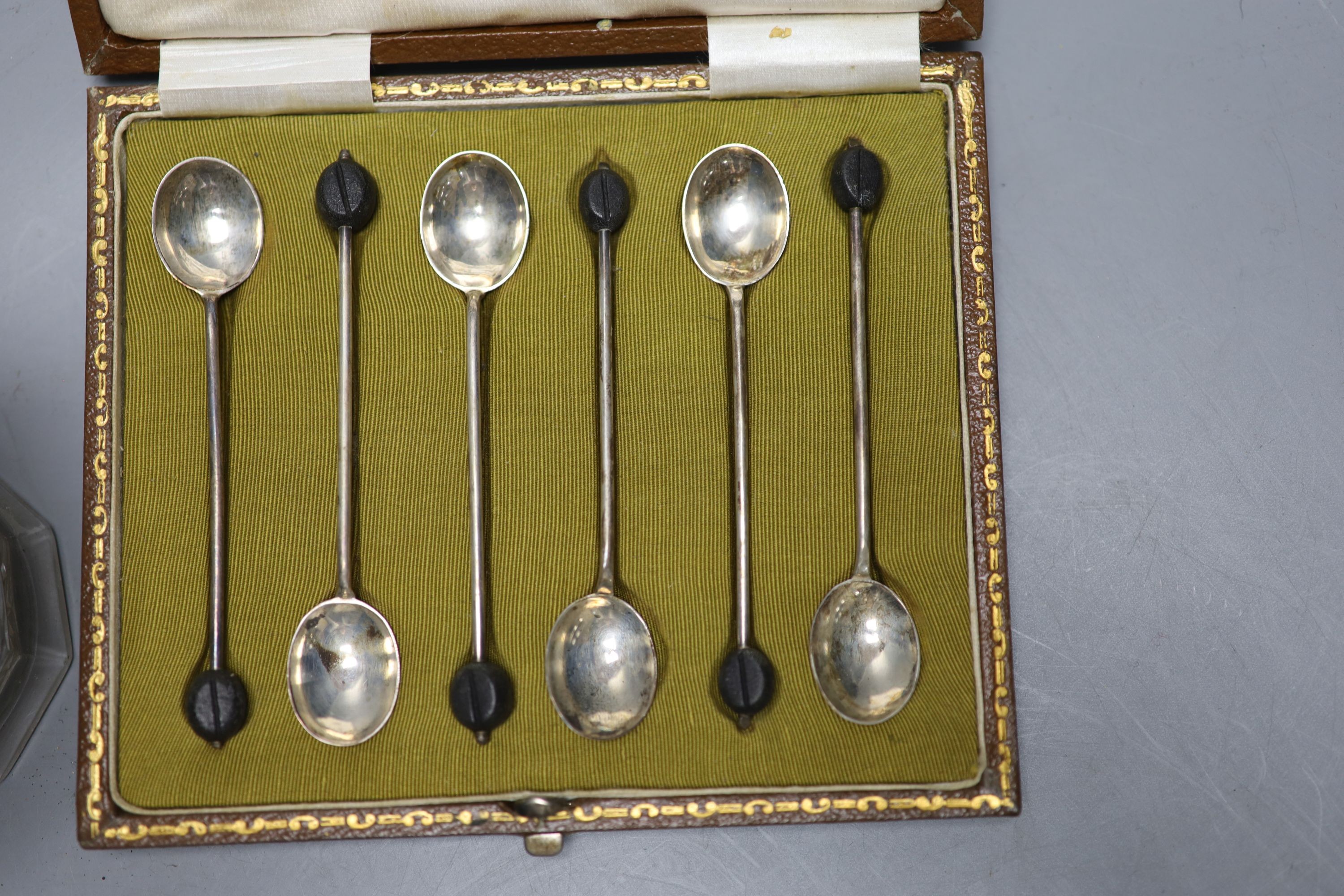 A cased set of six silver bean end coffee spoons and a George V silver mounted glass patent action sugar vase, (chipped foot).